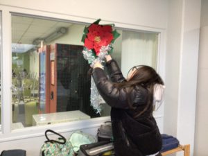 A student taking down a red paper flower decoration from a window