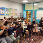 Students sitting, playing string instruments