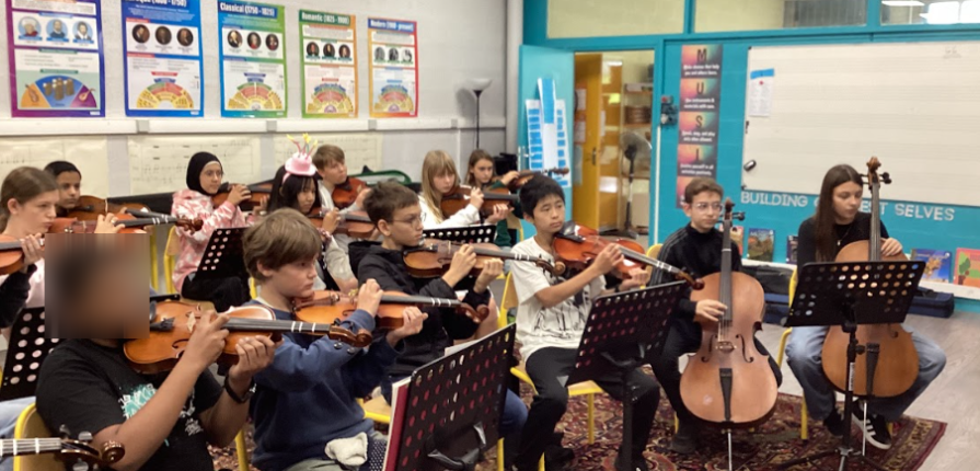 Students sitting, playing string instruments