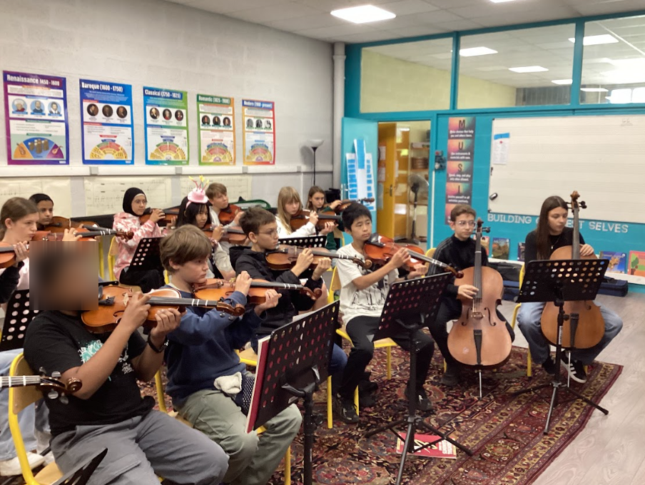 Students sitting, playing string instruments