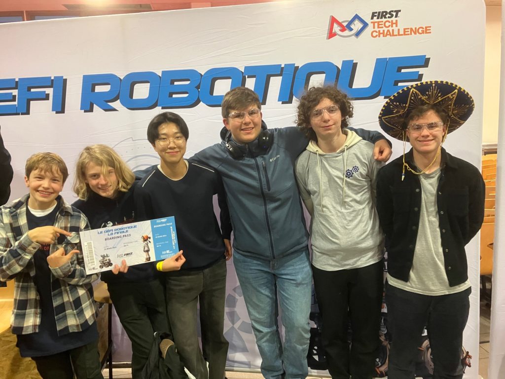 Students from the ISL Robotics team posing in front of a sign reading "First Tech Challenge Robotique"